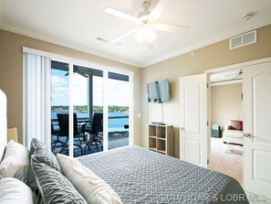 Relax in this inviting room with a large bed, ceiling fan, and wall-mounted TV, plus an outdoor area with a water view.