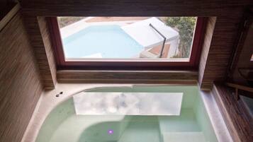 En vy genom ett fönster som visar en del av ett spa med ett bubbelbad och en pool.