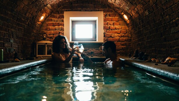 Una piscina techada de paredes de piedra con un pequeño ventanal al fondo.