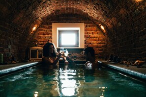 A stone-walled indoor pool with a small window at the far end. - Relais Villa Prato (Mombaruzzo)