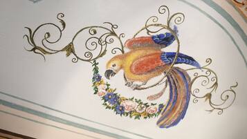 A ceiling with a painted bird surrounded by floral patterns and swirls.