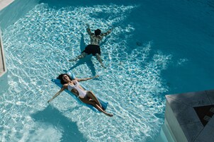 Vista aérea de uma piscina com duas pessoas boiando na água.