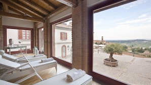 Una habitación con terraza, muebles de mimbre, un árbol en maceta y vistas al campo.