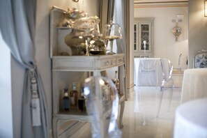 A well-lit, elegant room with a white table set for dining, a mirror, and a decorative cabinet with glassware. - Relais Villa Prato (Mombaruzzo)