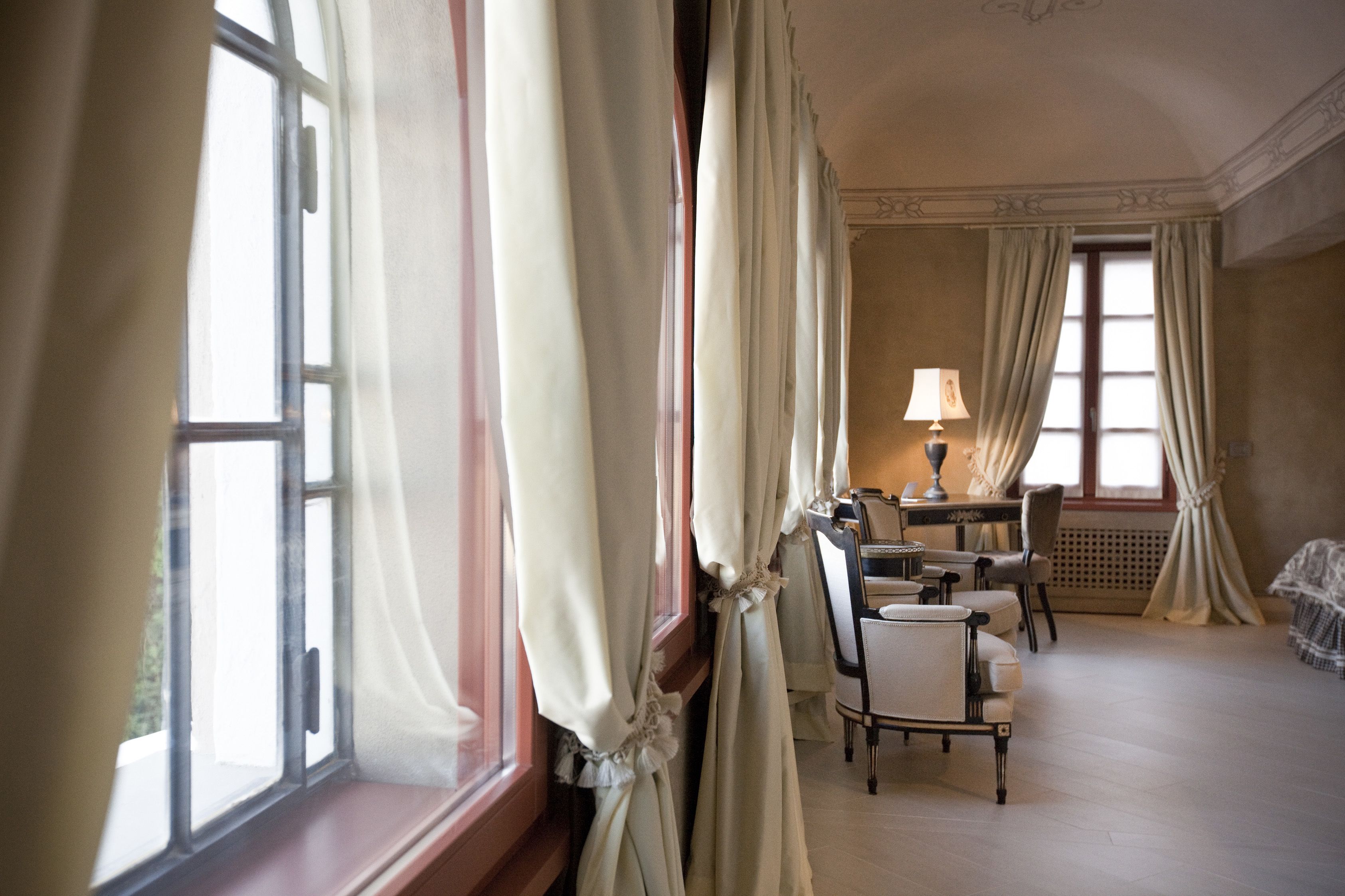 Ein Zimmer mit großen Fenstern, einem Tisch mit Stühlen und einer Lampe.