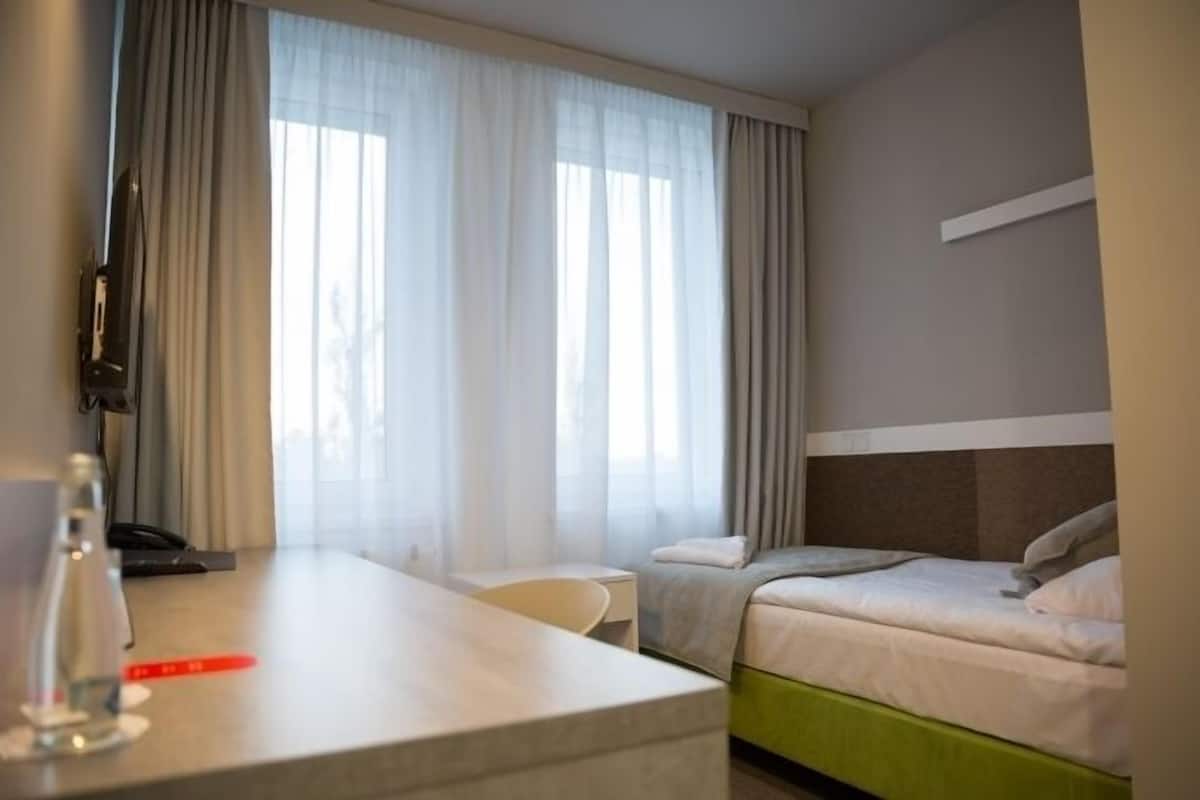 Ett hotellrum med en säng, ett skrivbord, en stol och en tv.