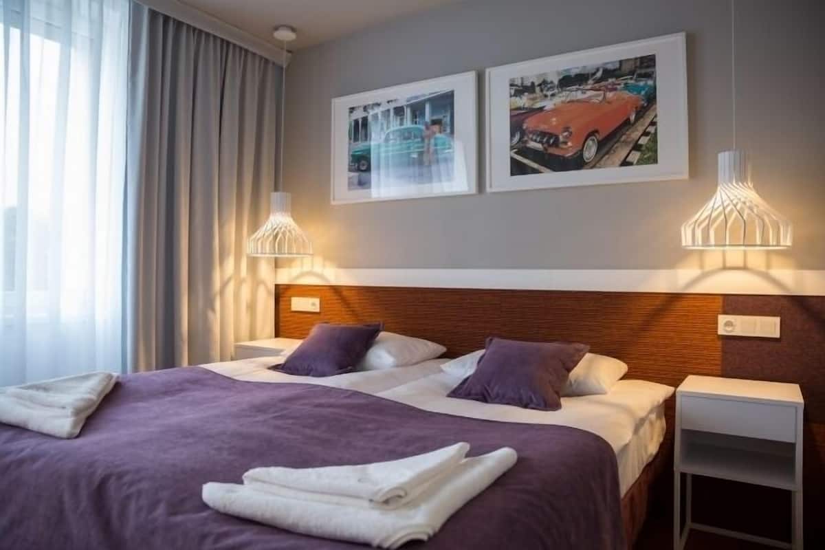 Ett hotellrum med en stor säng, två sidobord och två väggmonterade lampor.