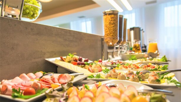 Buffet com diversos pratos, incluindo carnes, saladas e frutas.