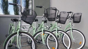 Uma fileira de bicicletas verdes com cestas, estacionadas em frente a um edifício com janela.