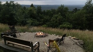 An outdoor seating area with a fire pit, benches, and chairs.