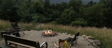 An outdoor seating area with a fire pit, benches, and chairs.