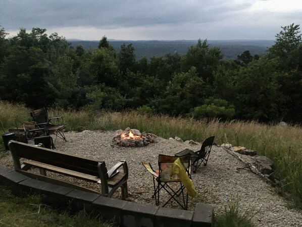 An outdoor seating area with a fire pit, benches, and chairs.