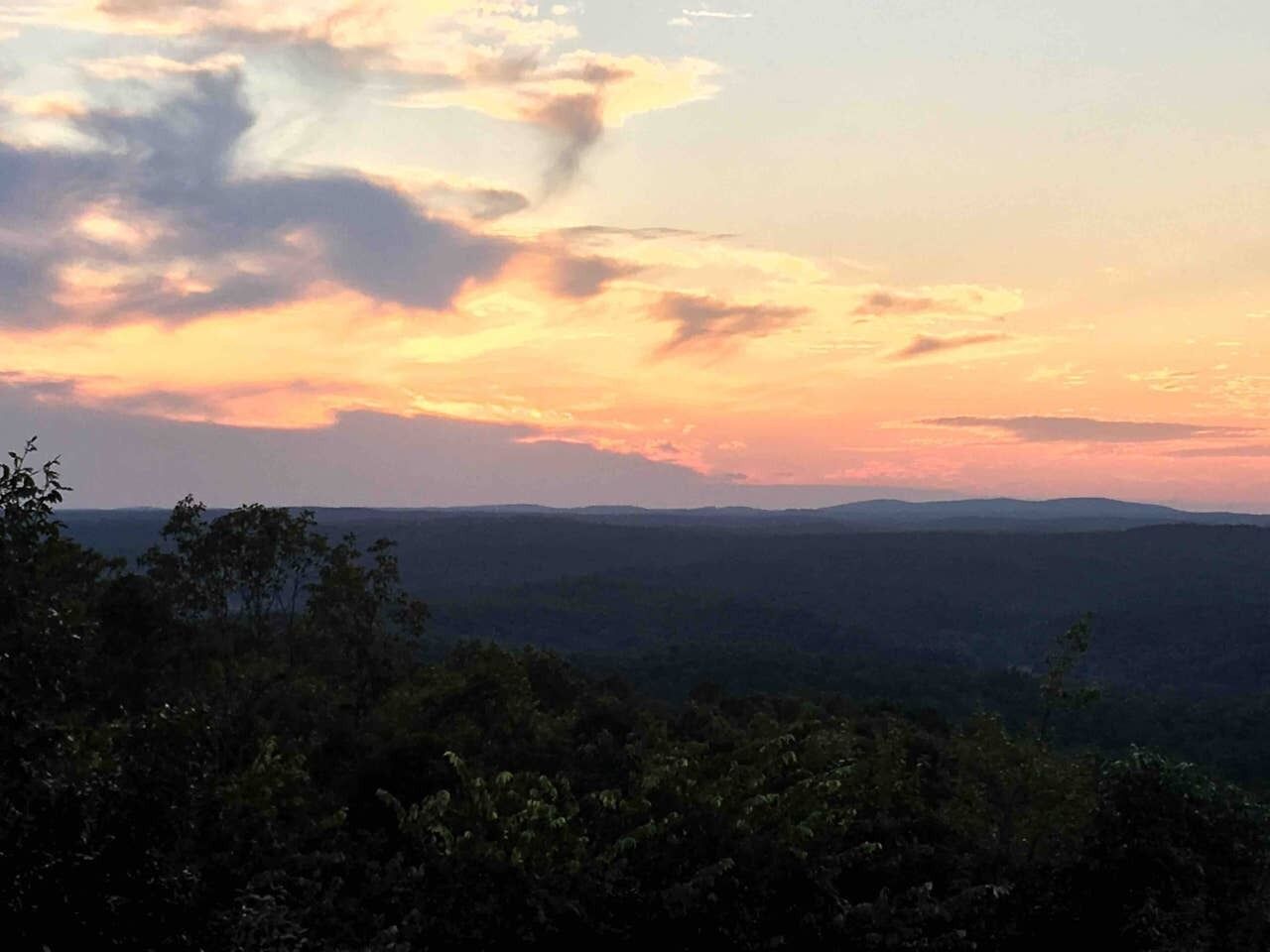 Une vue panoramique sur un paysage, avec un coucher de soleil et des collines lointaines.