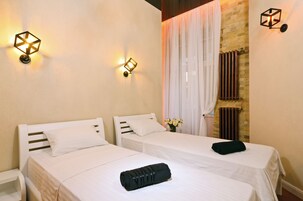 Una habitación con dos camas, una mesita de noche y una lámpara fijada a la pared.