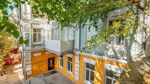 Un patio con un edificio amarillo, una escalera y un árbol.