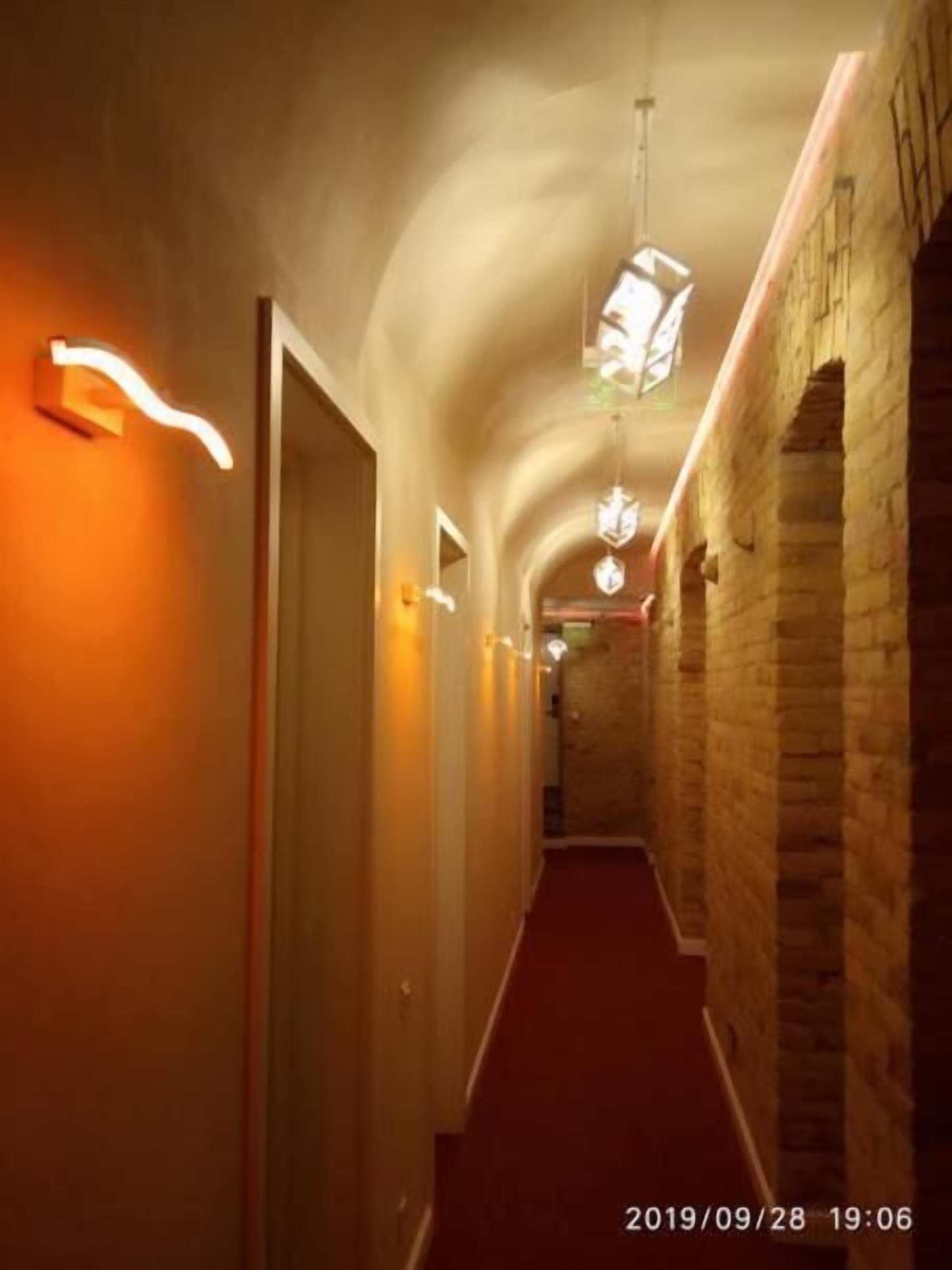 Um corredor com tetos abobadados e paredes de pedra, que leva a uma porta no final.