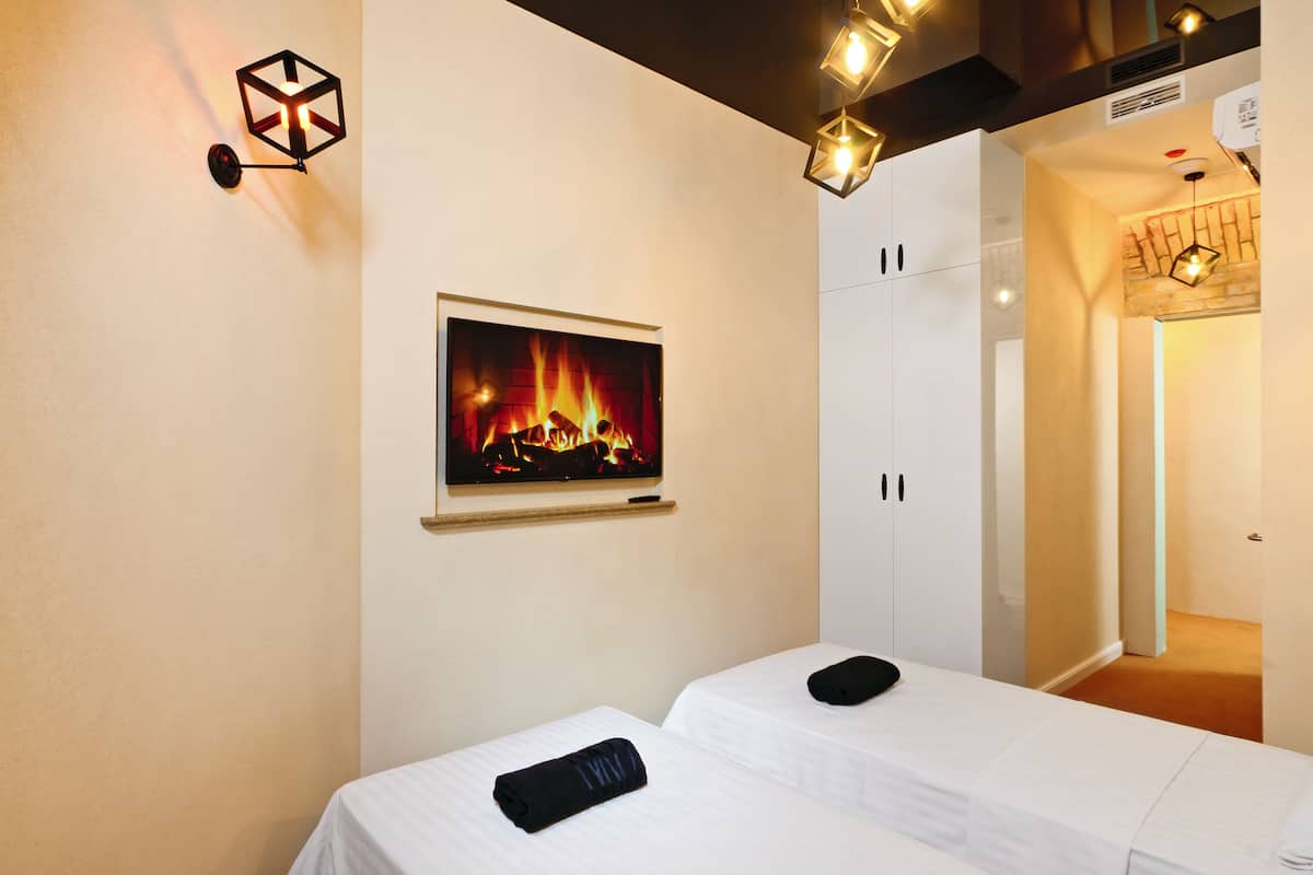 A hotel room with a fireplace, a bed, a small table, and a wardrobe.