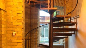 Una escalera de caracol con escalones de madera y barandillas de metal, que conduce a un piso superior.