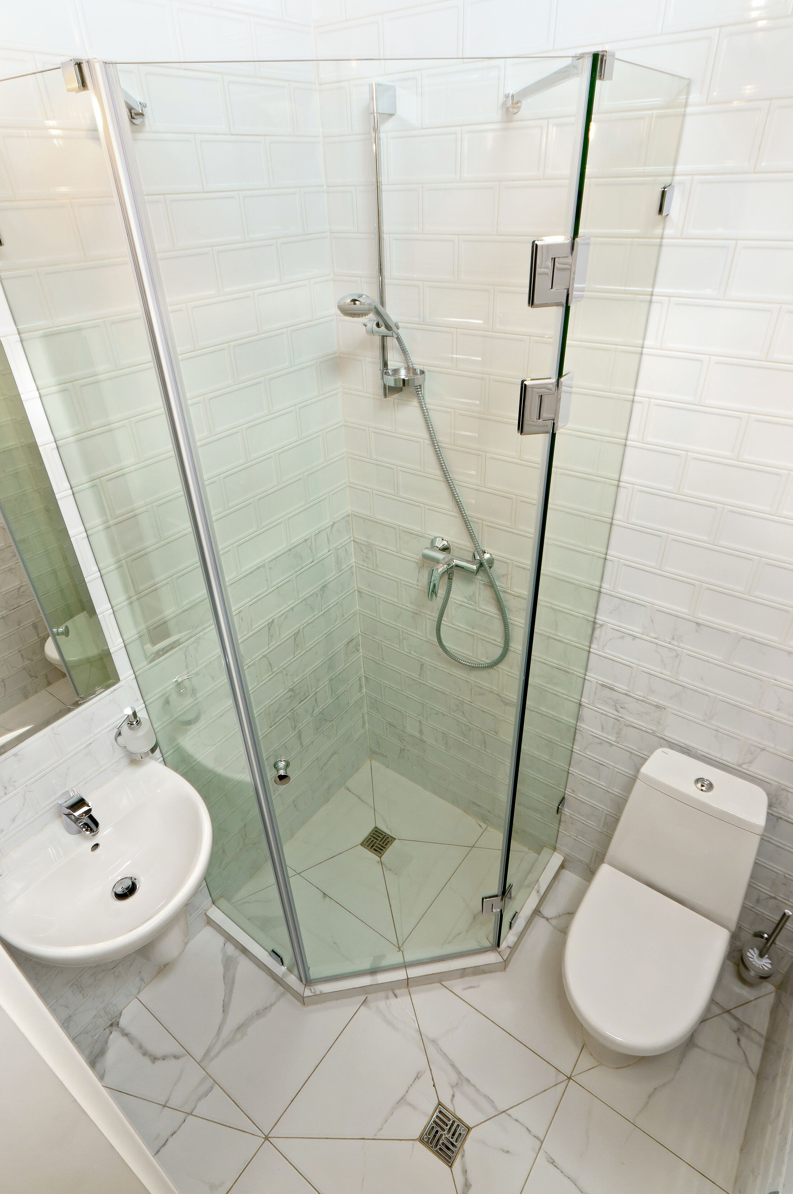 Un baño moderno con ducha de vidrio, lavamanos blanco y retrete.