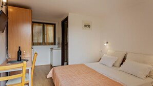 A bedroom with a bed, bedside table, and a small desk with a chair. There is a window with blinds, a sink, and a framed picture on the wall. - Room in Rogoznica with WIFI (3338-5) (Rogoznica)