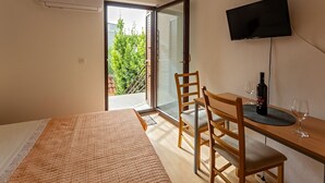 A bedroom with a bed, a desk, a chair, a TV, and a bottle of wine. - Room in Rogoznica with WIFI (3338-5) (Rogoznica)