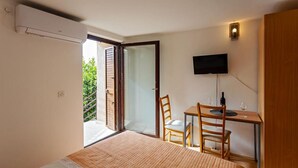 A bedroom with a bed, a desk with two chairs, a television, and a sliding glass door leading to a balcony. - Room in Rogoznica with WIFI (3338-5) (Rogoznica)