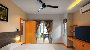 Una habitación de hotel moderna con una cama, televisión, ventilador de techo y vistas a un balcón.