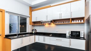Una cocina moderna con armarios blancos, encimeras negras y electrodomésticos de acero inoxidable.
