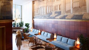 A spacious lobby with a modern blue sofa set, a large wall mural, and a staircase. - Brown Acropol, a member of Brown Hotels (Athens)
