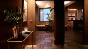 A modern interior with a wooden floor, a dining area with a table and chairs, a kitchen area with a bar, and a large window providing a view. - Brown Acropol, a member of Brown Hotels (Athens)
