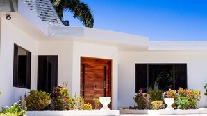 Uma casa moderna com porta de madeira, paredes externas brancas e um jardim bem cuidado.