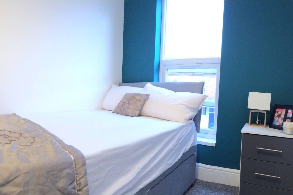 A bedroom with a bed, a chair, a wardrobe, and a window.