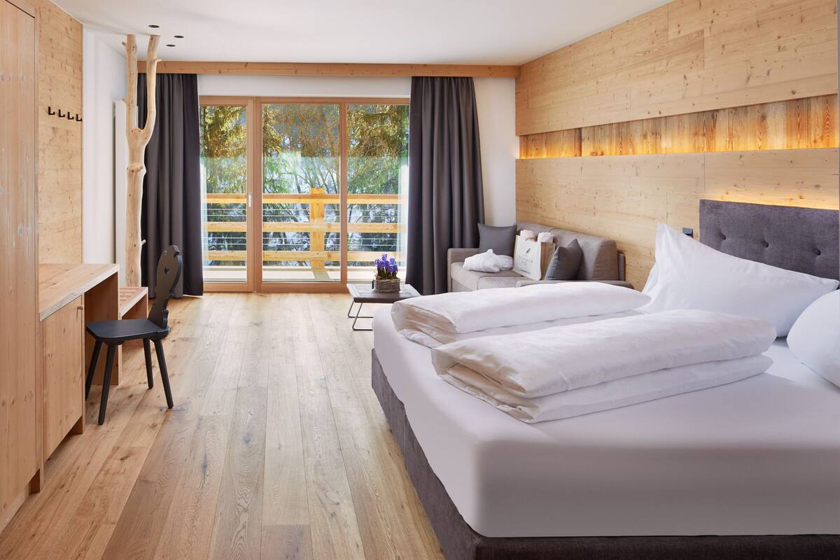 Une chambre d’hôtel moderne, dotée d’un grand lit, d’un bureau et offrant une vue sur l’extérieur.