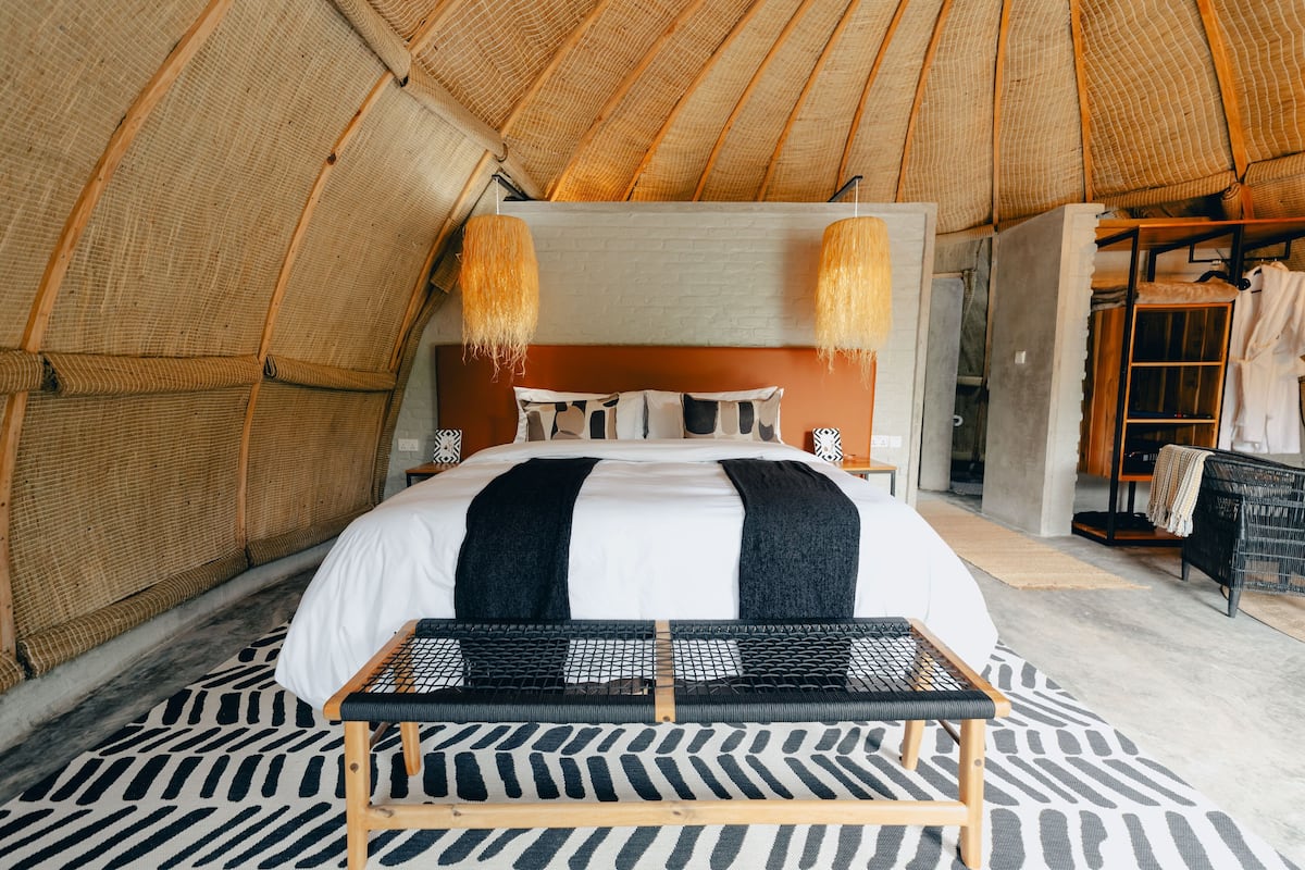 A spacious, well-lit room with a large bed, a bench, and a wardrobe.