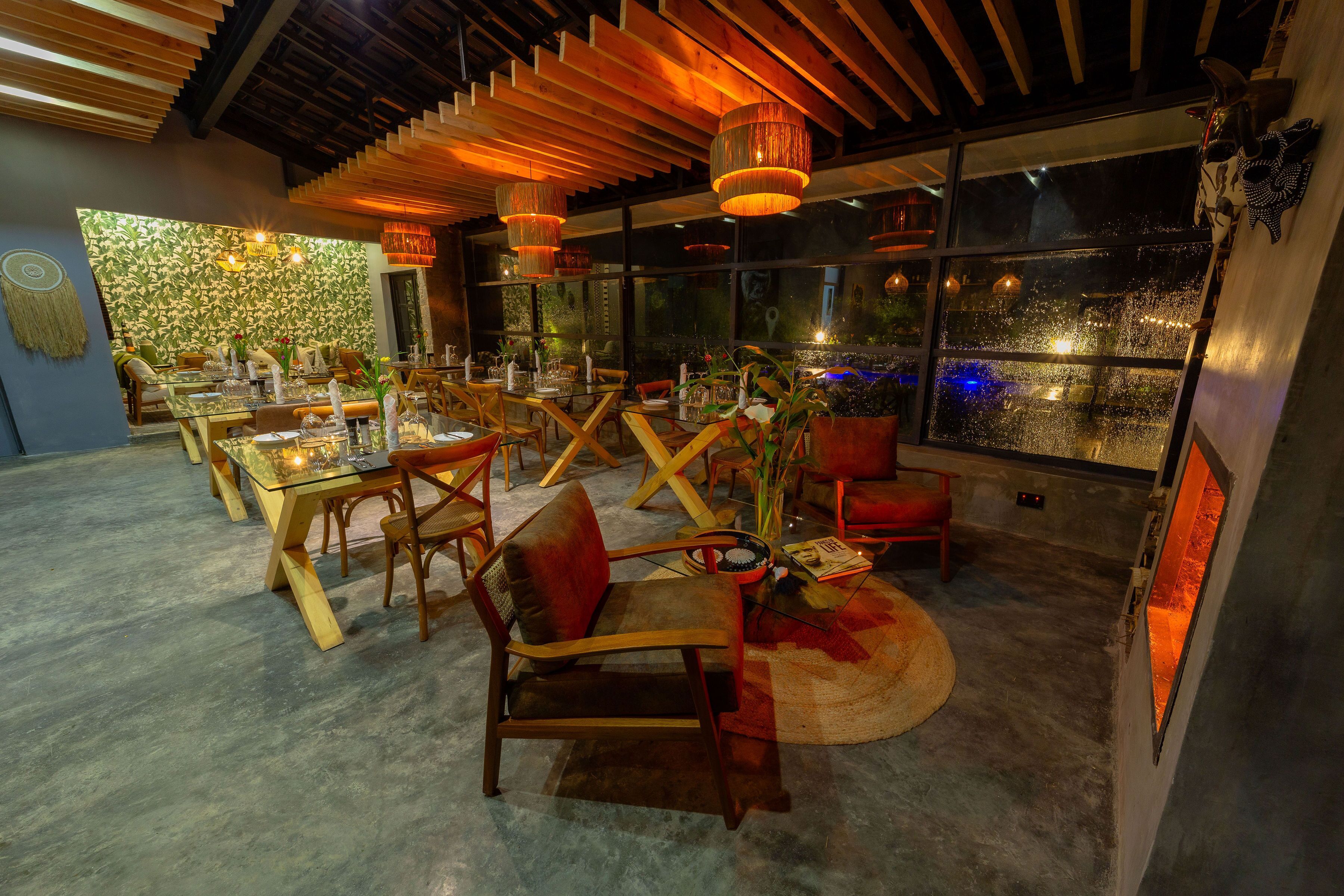 A modern dining area with wooden furniture, glass tables, and hanging pendant lights.