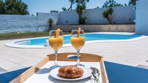 A tray with two glasses of orange juice, a croissant, and a glass of water on a table by a pool. - Luxurious home in Betina (Betina)