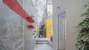 A narrow hallway with steps leading to a door, decorated with potted plants and red shelves. - Liiiving - Clérigos Terrace Apartment (Porto)