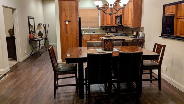 A dining area with a wooden table and chairs, a chandelier, and wooden cabinets in the background. - Beautiful ground floor condo in St. George, Utah (St. George)