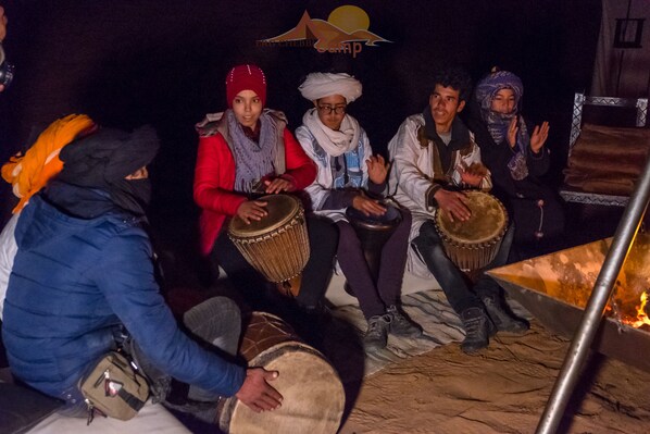 Un grupo de personas sentadas alrededor de una fogata, tocando la batería.