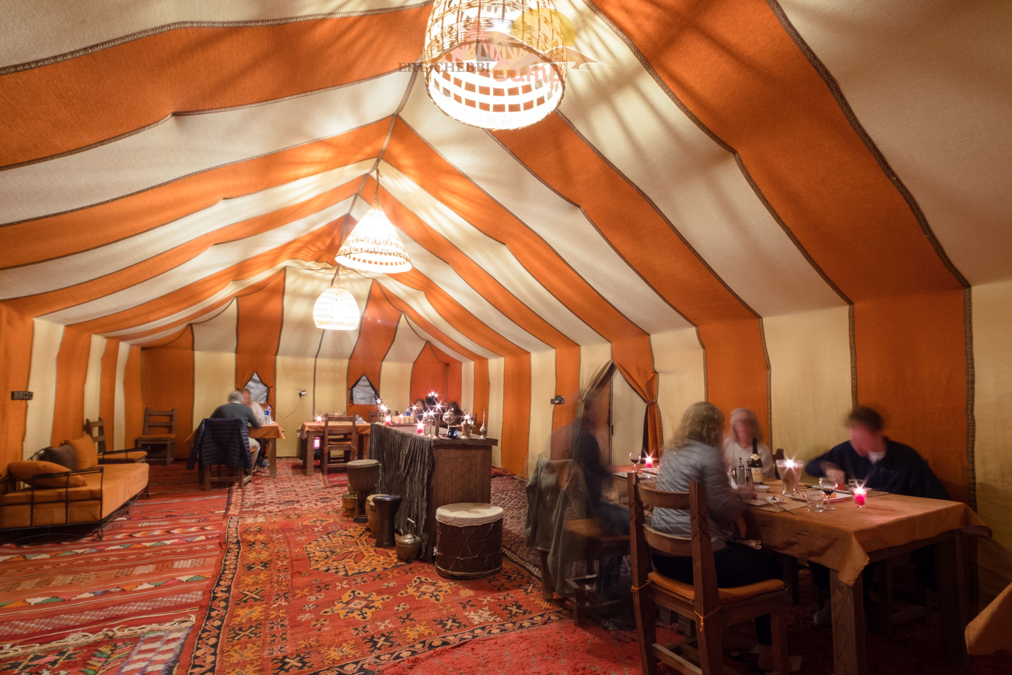 A tented dining area with tables, chairs, and a chandelier.