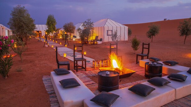 A desert resort with outdoor seating, a fire pit, and tents. - Erg Chebbi Camp (Taouz)