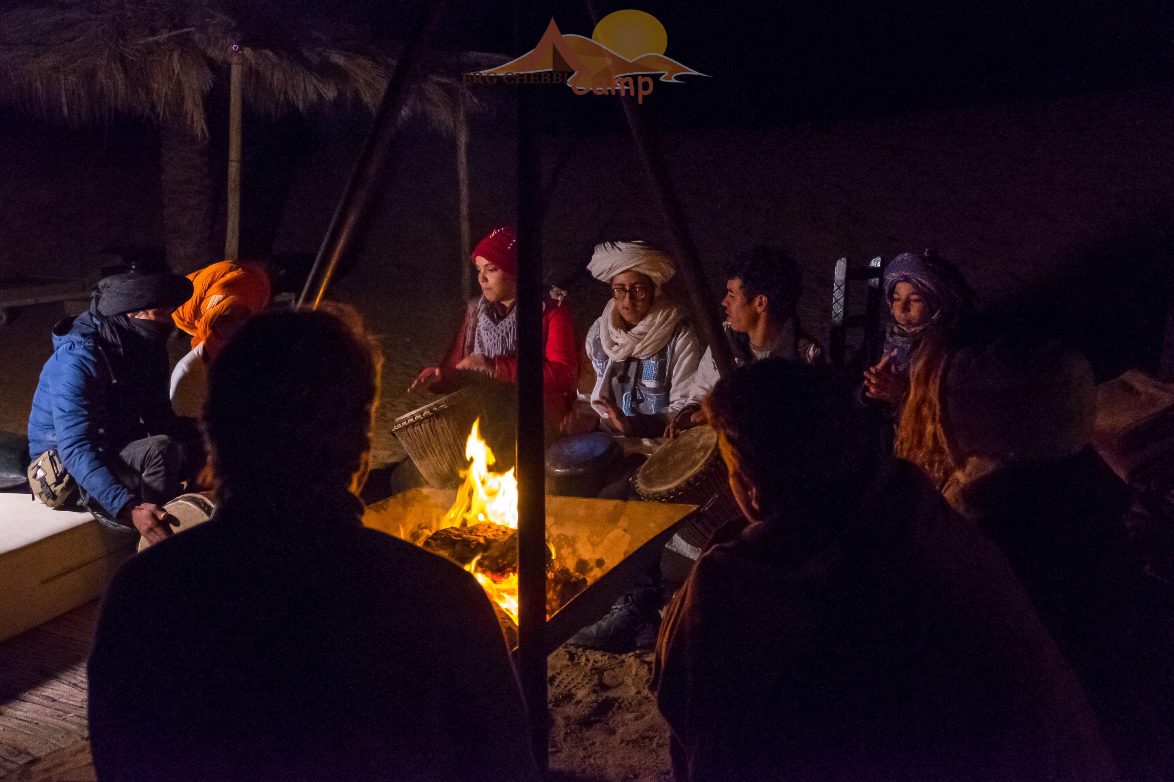 A group of people gathered around a campfire at night.