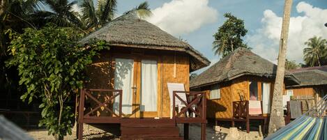 A beachside hut with a thatched roof, wooden deck, and a small porch.