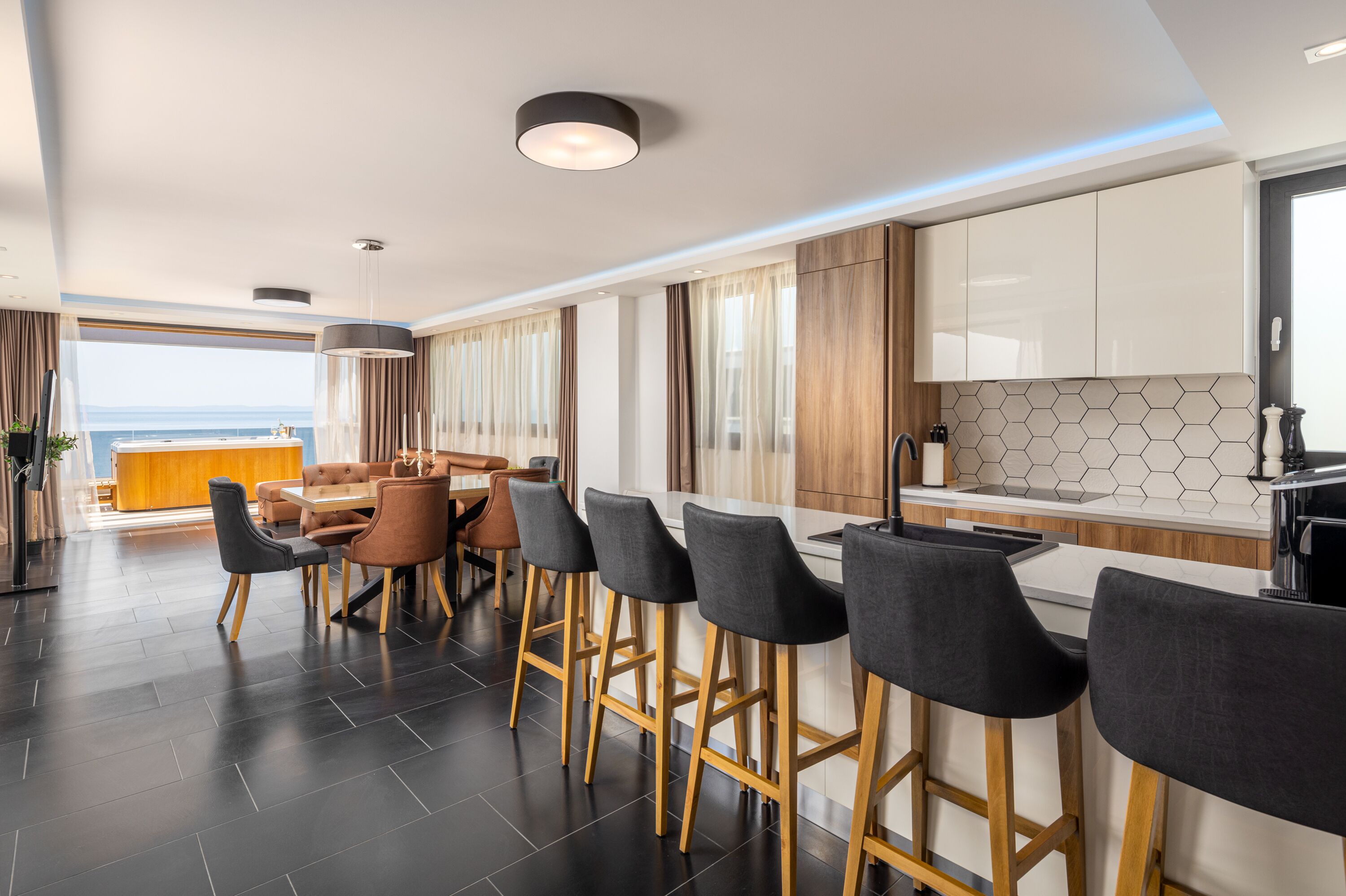 Una cocina moderna con barra, suelo de madera y vistas al mar.