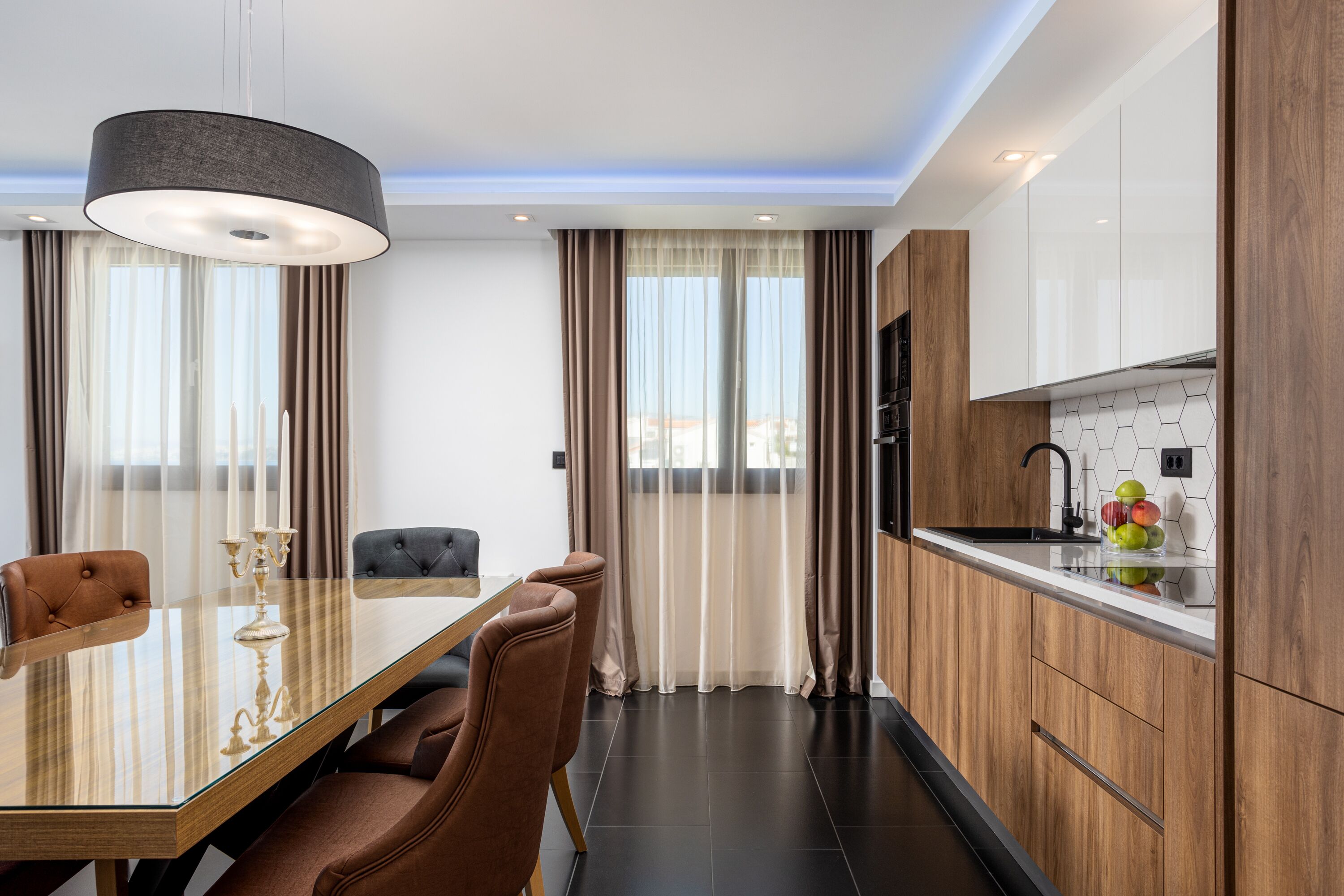 A modern kitchen with wooden cabinets, a glass countertop, and a black faucet.