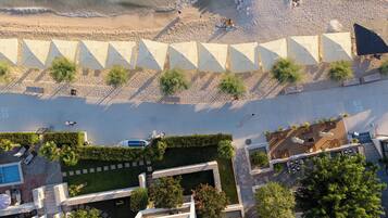 Vista aérea de un resort con múltiples sombrillas de playa, una zona de piscina y un jardín ajardinado.