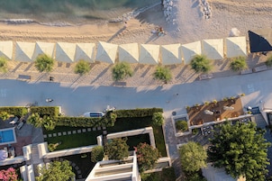 Vista aérea de un resort con múltiples sombrillas de playa, una zona de piscina y un jardín ajardinado.