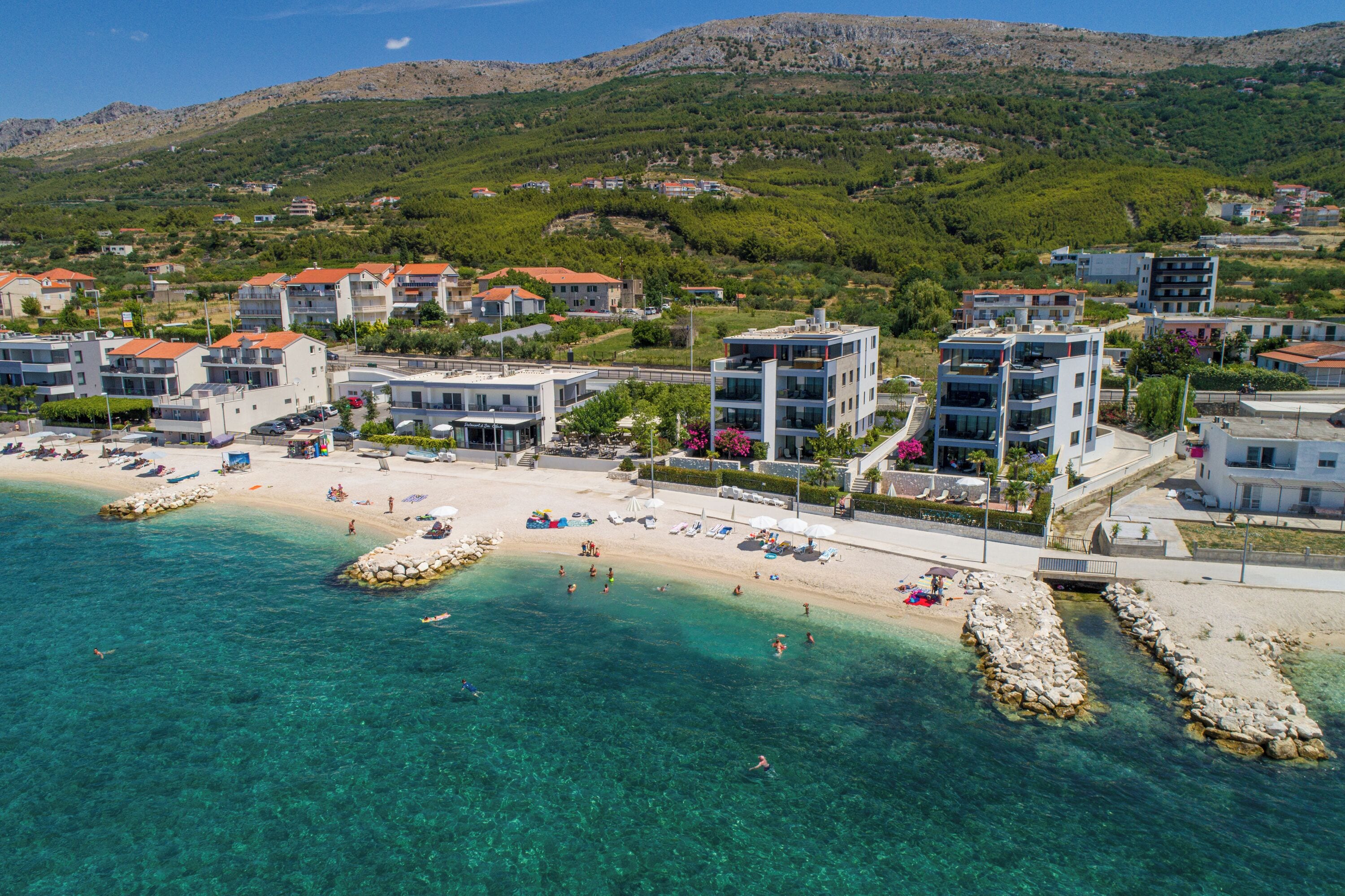 Una pittoresca località costiera con edifici, una spiaggia e acque cristalline.