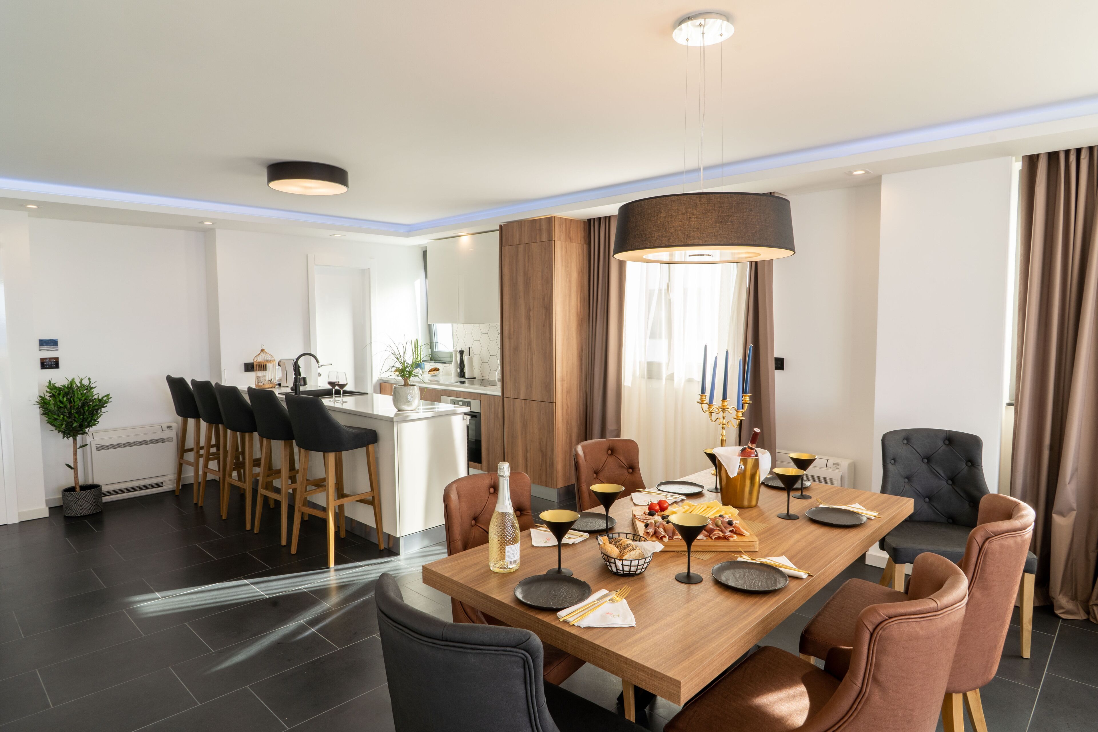 Uma sala de jantar moderna com mesa de madeira, cadeiras pretas e castanhas, e um candelabro.