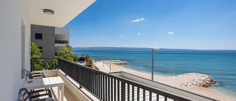 Un balcon avec vue sur la mer, une table et des chaises.